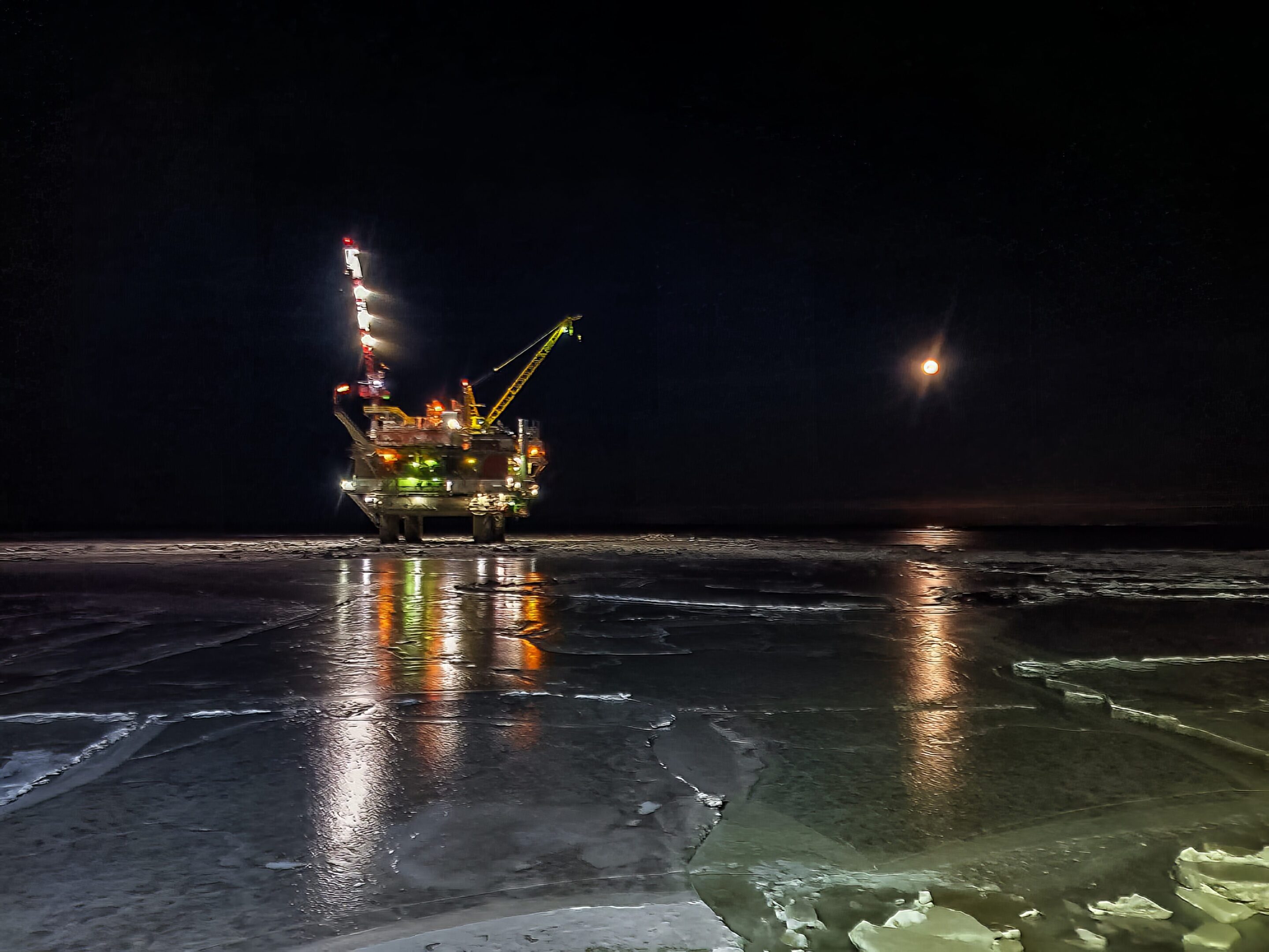 Nighttime oil rig and moonlit sky