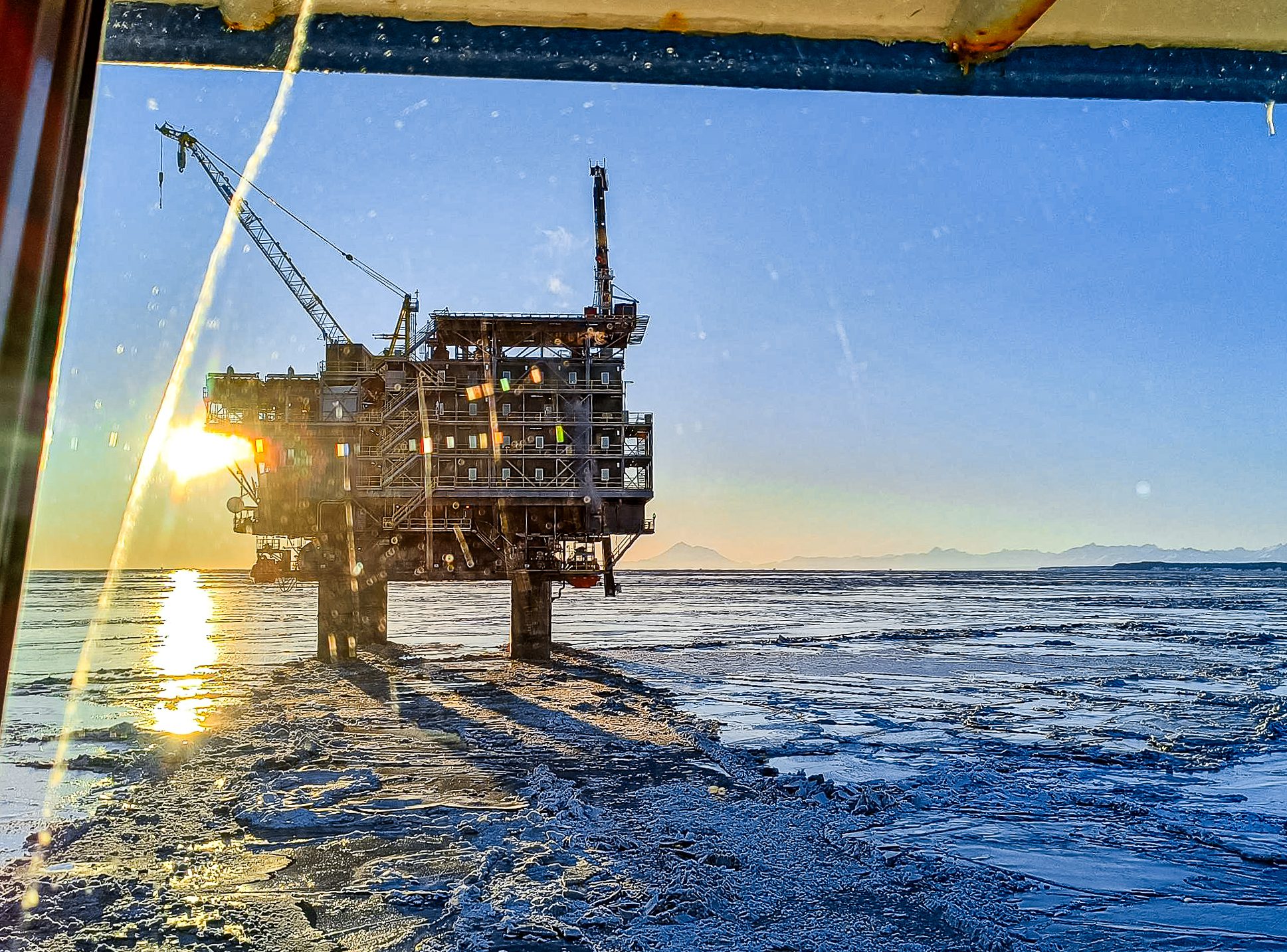 Oil rig silhouetted against sunset sky